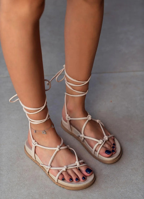 Beige PERRY Sandalen mit flacher Sohle und eleganten Schnürdetails, die um den Knöchel gebunden werden. Komfortables und trendiges Design für den Sommer.
