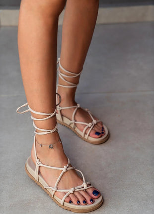 Beige PERRY Sandalen mit flacher Sohle und eleganten Schnürdetails, die um den Knöchel gebunden werden. Komfortables und trendiges Design für den Sommer.